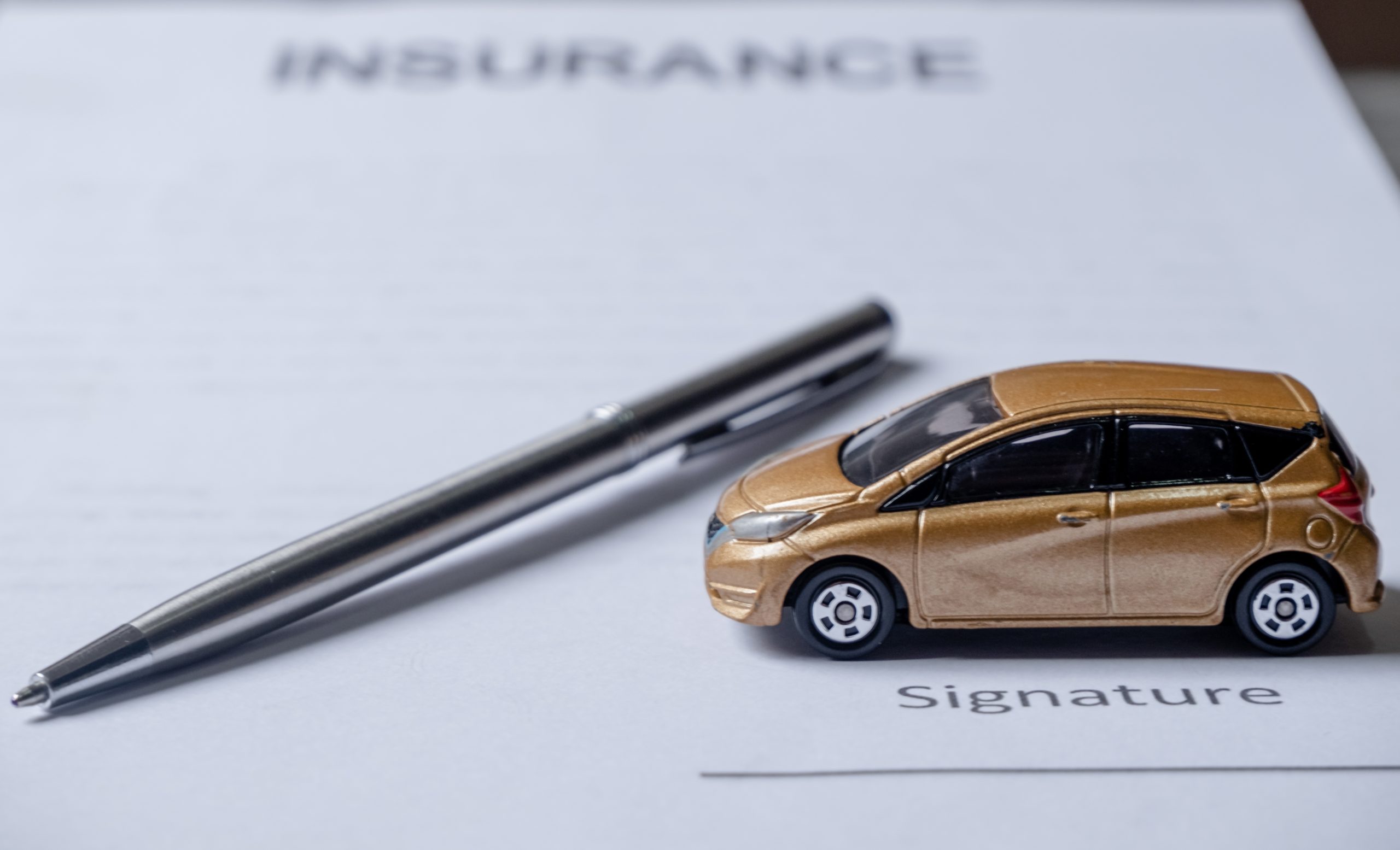 Car and pen on insurance documents. Car insurance conceptCar and pen on insurance documents. Car insurance concept